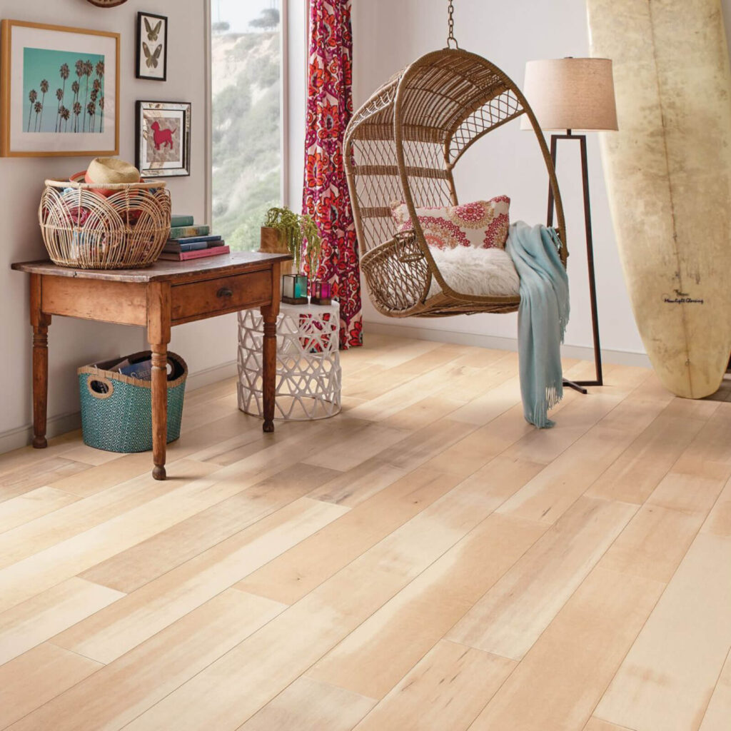 Colorful bohemian-style room with a wooden desk, hanging chair, and light blonde hardwood flooring.