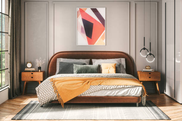 Modern bedroom with an orange bedspread, neutral decor, and a large area rug placed under the bed.